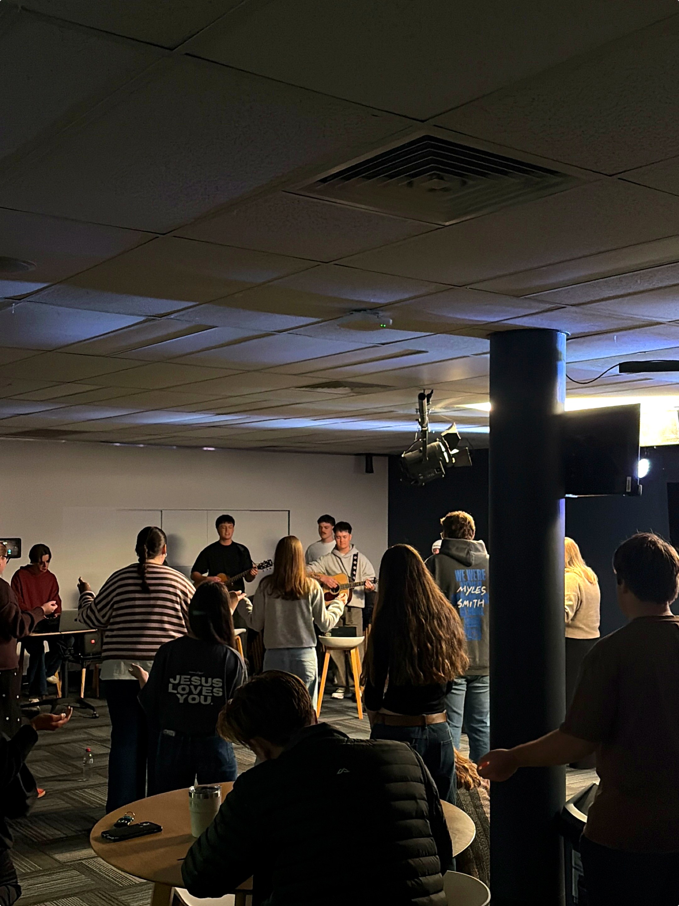 A room of young adults singing together with hands raised during 838 worship night